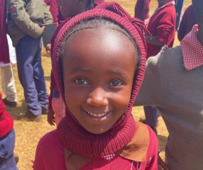 closeup of a young girl smiling at the camera in a burgundy knit hat and sweater